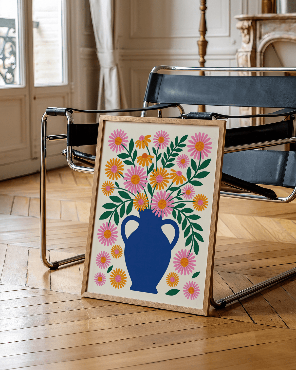 Framed Vase Art Print leaning on a modern black chair with orange and pink flowers