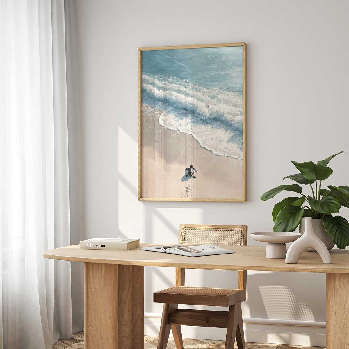 Turtle print showing a baby sea turtle on a sandy beach with blue waves above a wooden table and plant