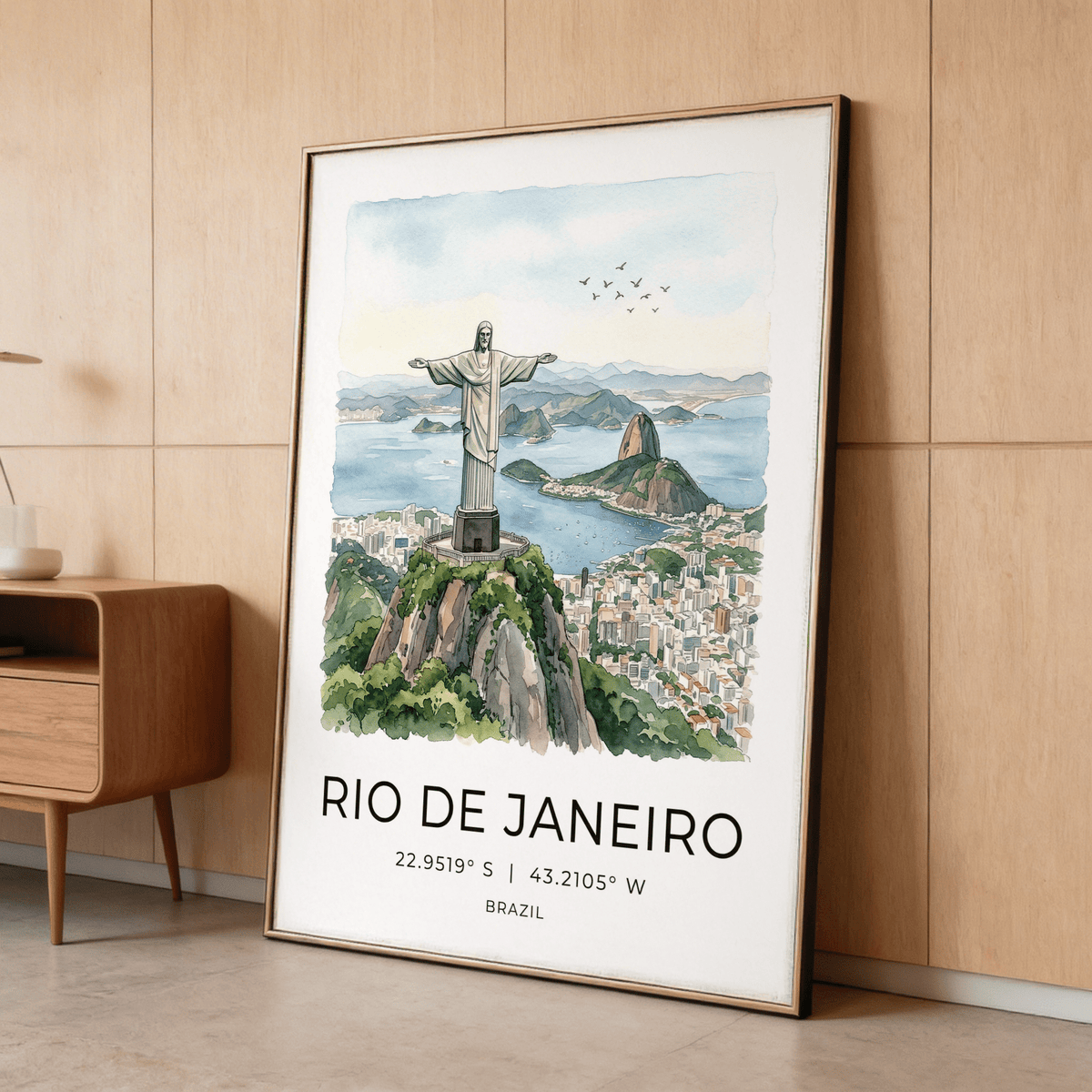 Framed Cristo Redentor Poster with watercolour illustration leaning on a wooden floor by a cabinet