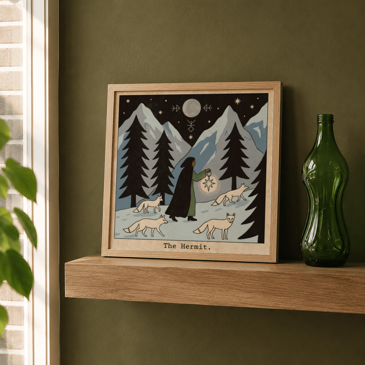 Framed The Hermit Tarot Card Art print with a dark-cloaked figure holding a glowing lantern and foxes on a wooden shelf with a green glass