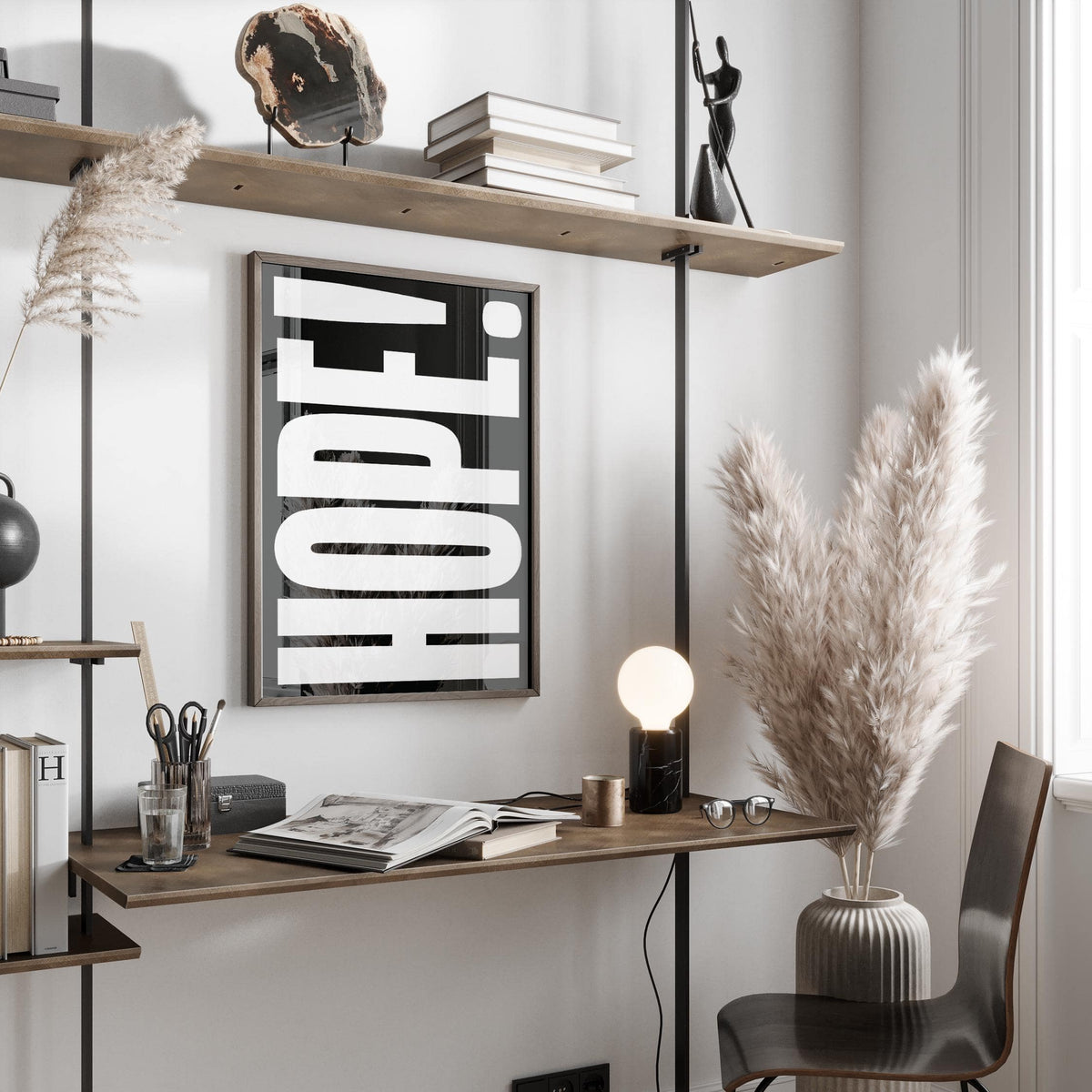 Inspirational Artwork print with white HOPE text on black leaning above a wooden desk and next to a vase with pampas grass