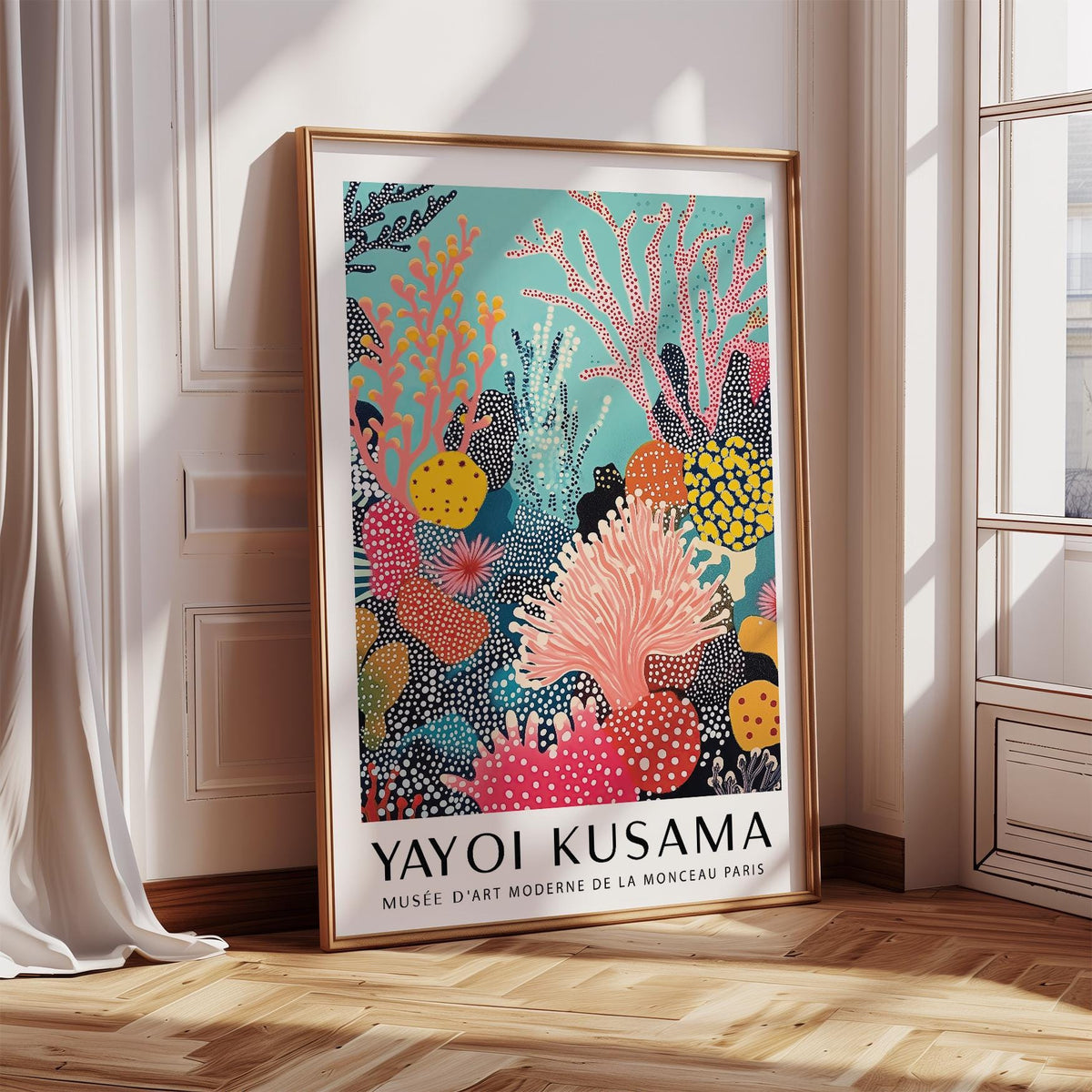 Bright wall art leaning on a wooden floor showing abstract coral reef with pink and yellow hues near a sunlit window