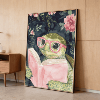 Print leaning on floor of turtle reading art print with pink glasses and flower background beside wooden cabinet