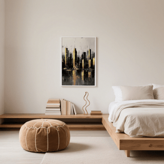 Gold and black skyline poster hanging above a low wooden shelf with books and a decorative object in a bedroom