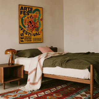 Frida Kahlo art print with a woman playing guitar in bright yellow above a bed with a green bedspread and wooden lamp