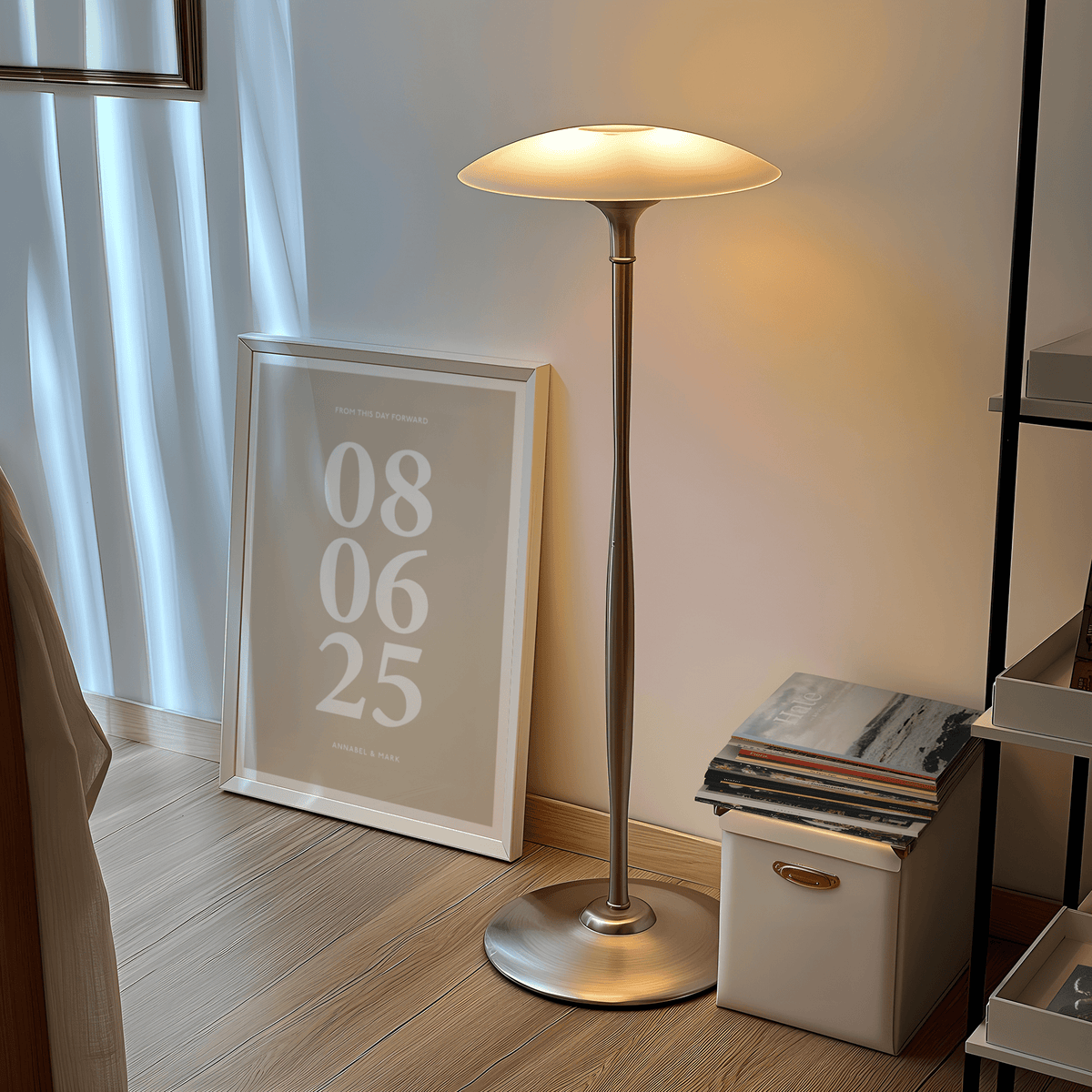 Framed print of anniversary date in white on beige leaning on floor near a lamp and stack of books