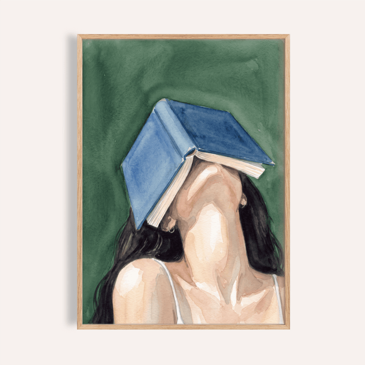 Framed print of woman reading portrait print with a blue book covering her face against a green background