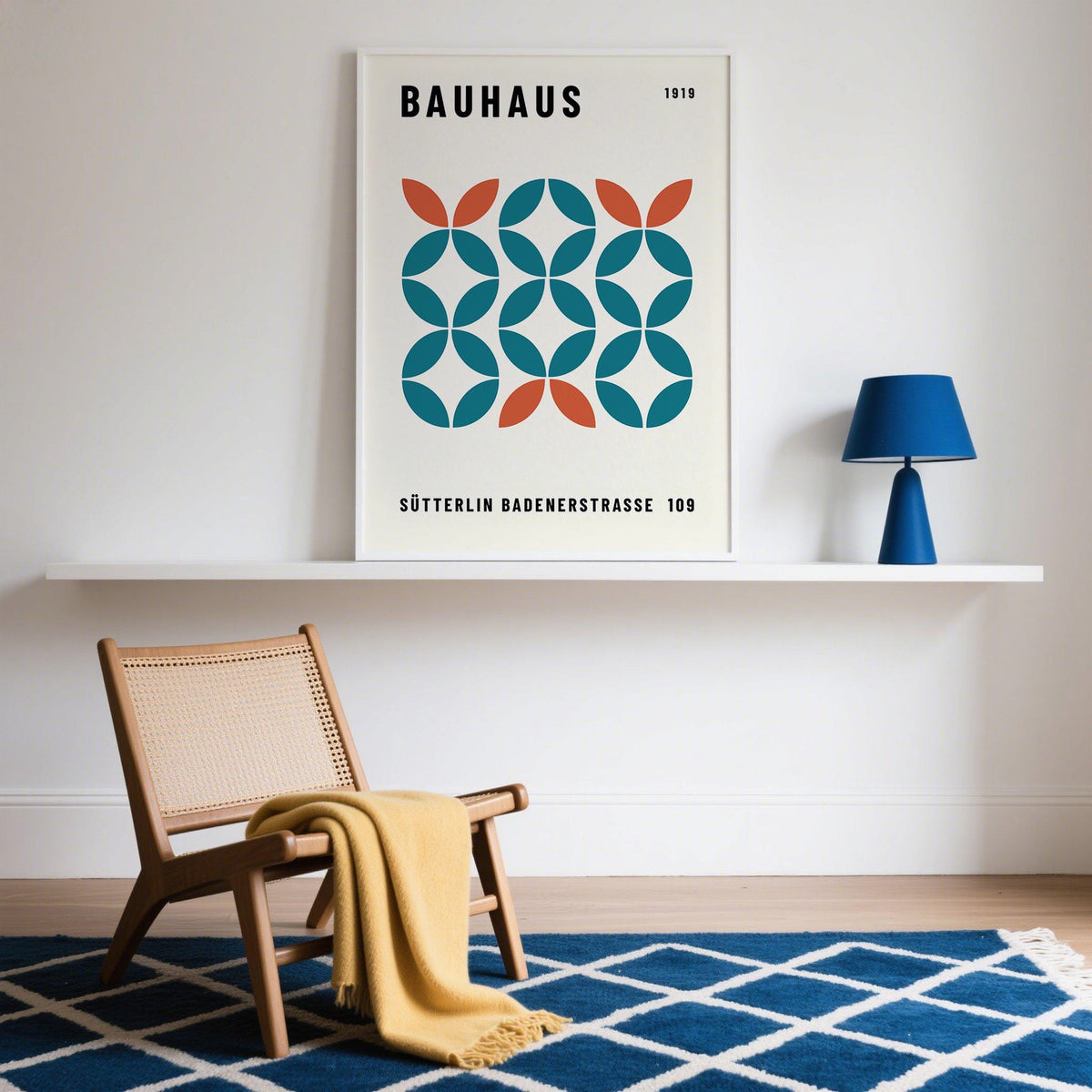 Work Office Wall Art framed print with geometric shapes in blue and orange on a white shelf next to a blue lamp