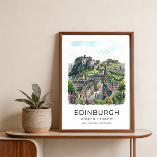 Framed Edinburgh Cityscape Art Print of a watercolour Edinburgh castle landscape on a wooden table with a plant