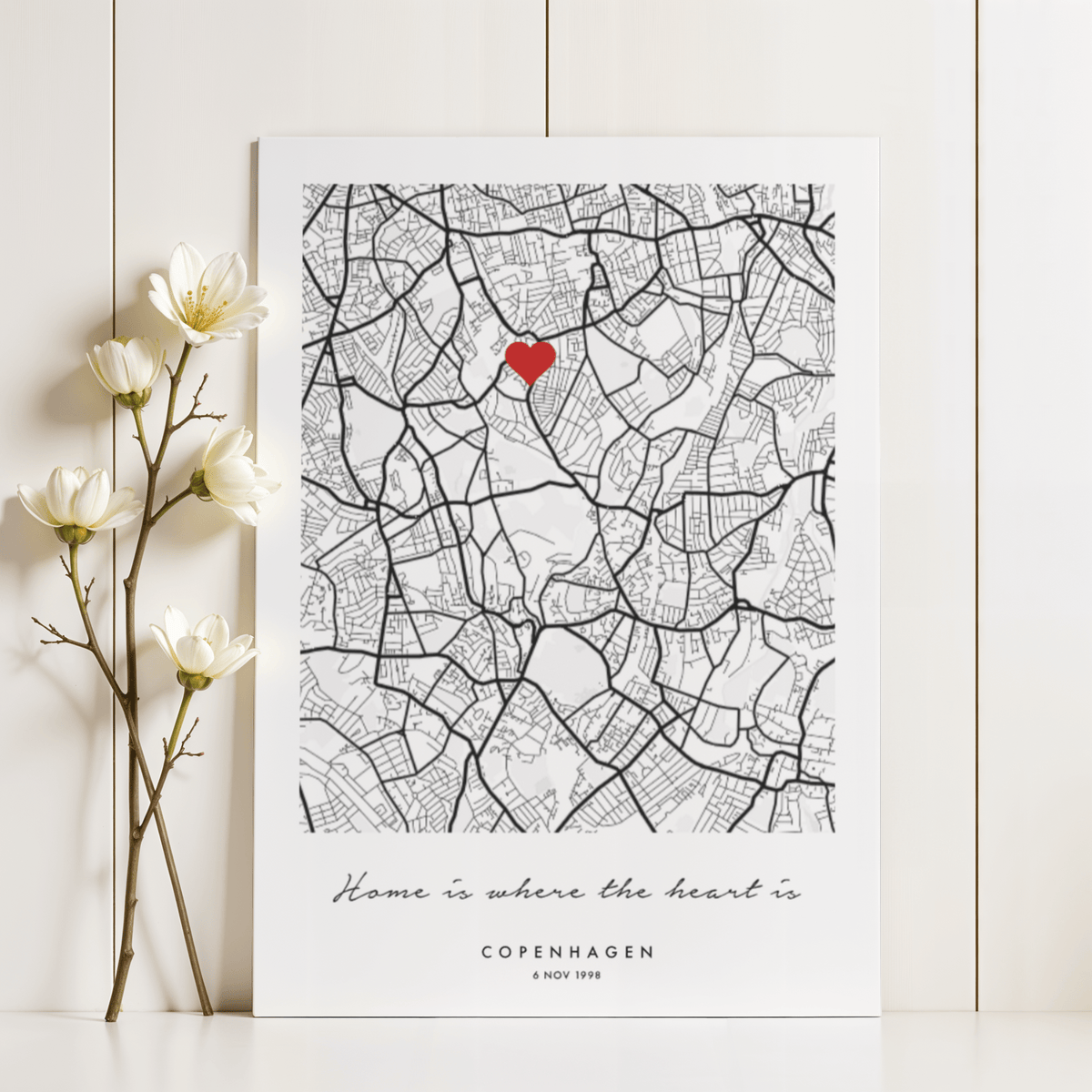 Anniversary Map Print leaning on wall with flowers nearby showing black and white city map with red heart