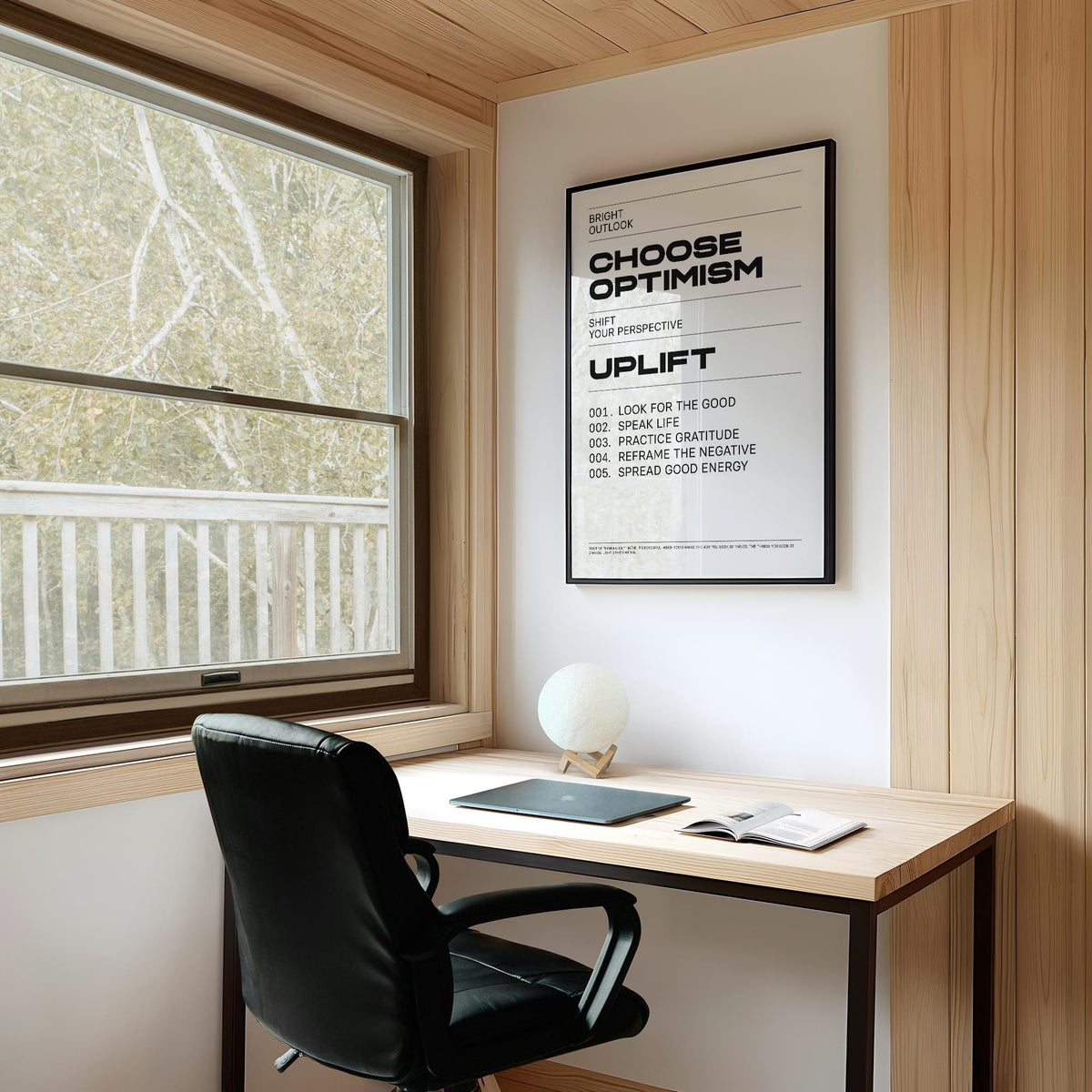 Uplifting wall art with Choose Optimism text in black and white above a desk with a black chair
