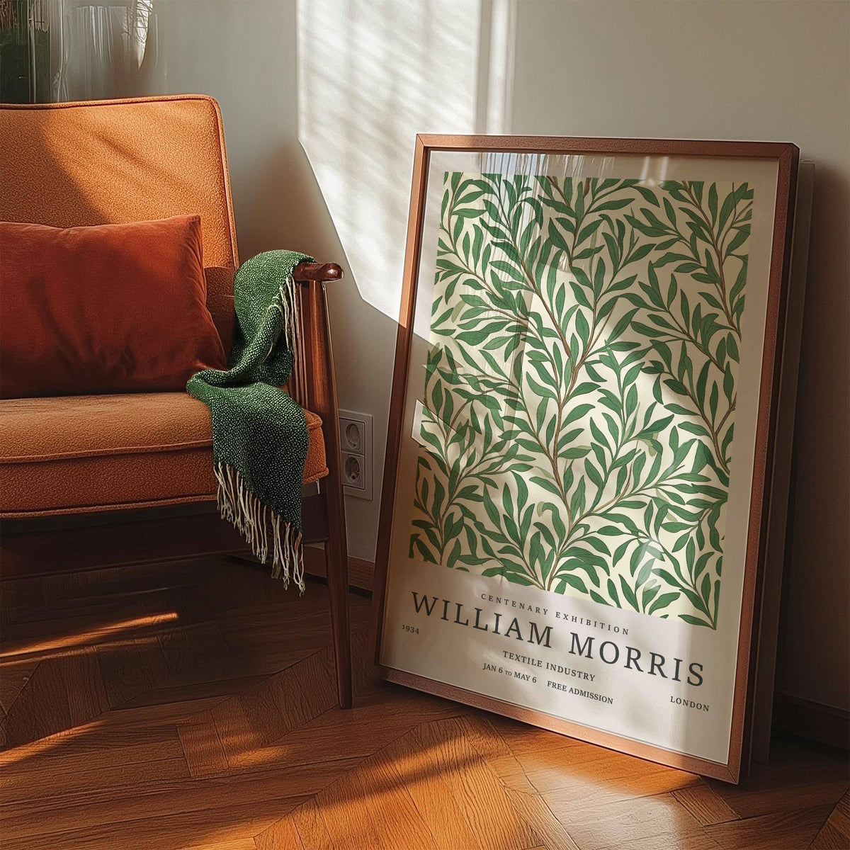 Classic Art Posters print leaning on wooden floor near an orange armchair with green throw in sunlight
