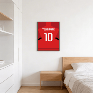 Football Shirt Poster in Red with Black Sleeve Bands hanging above a bedside table in a bedroom