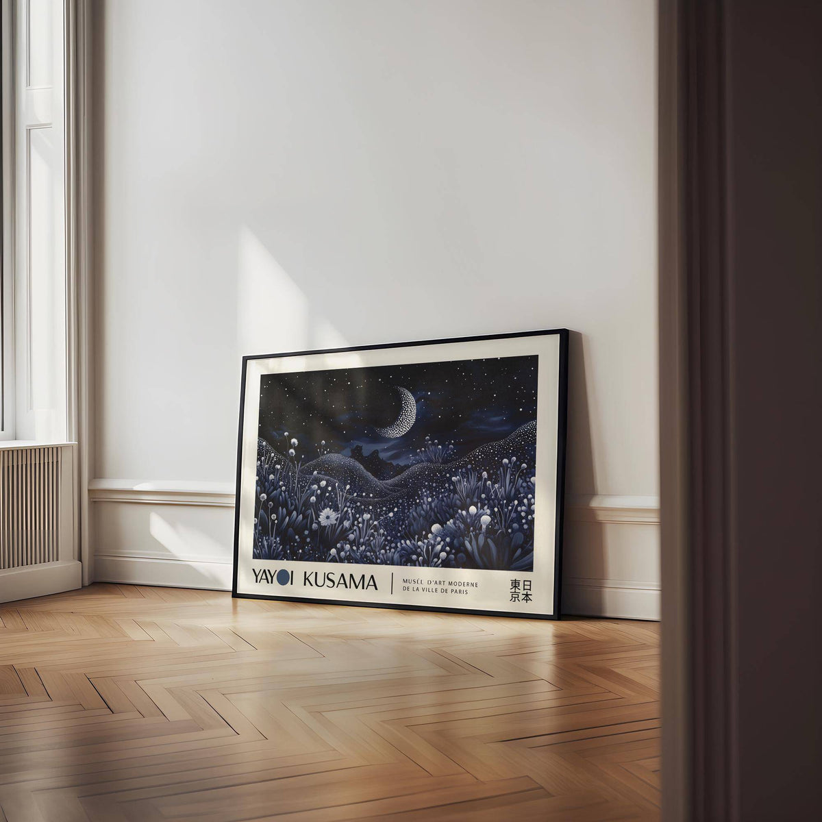 Print leaning on a wooden floor showing a crescent moon over floral hills in blues and whites