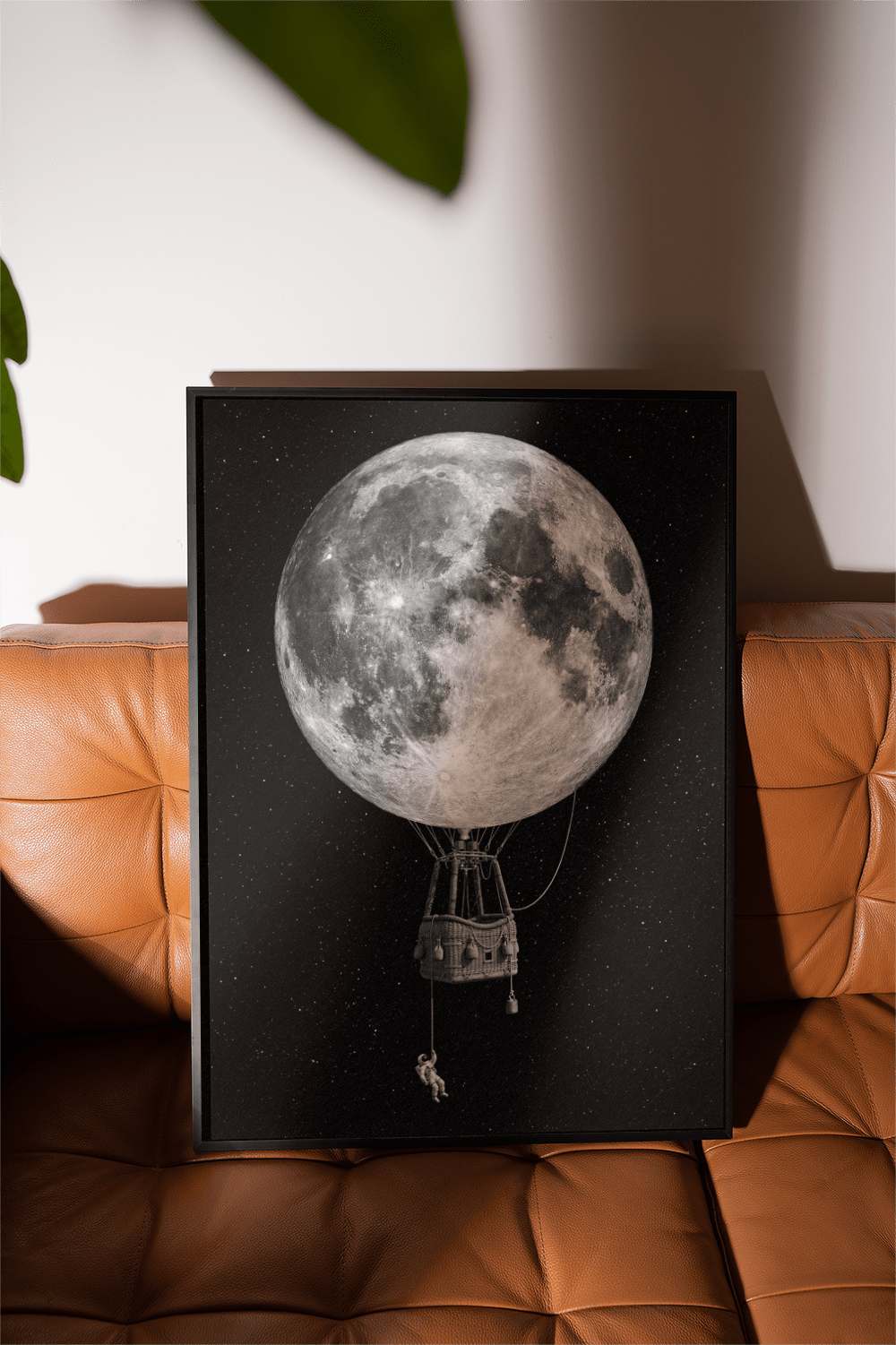 Moon Hot Air Balloon Art framed close-up with a brown leather sofa and green leaf