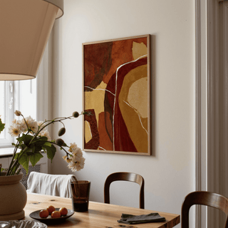 Abstract Earth Tones Print on a dining room wall featuring earthy brown and beige abstract shapes with a wooden frame and dining table