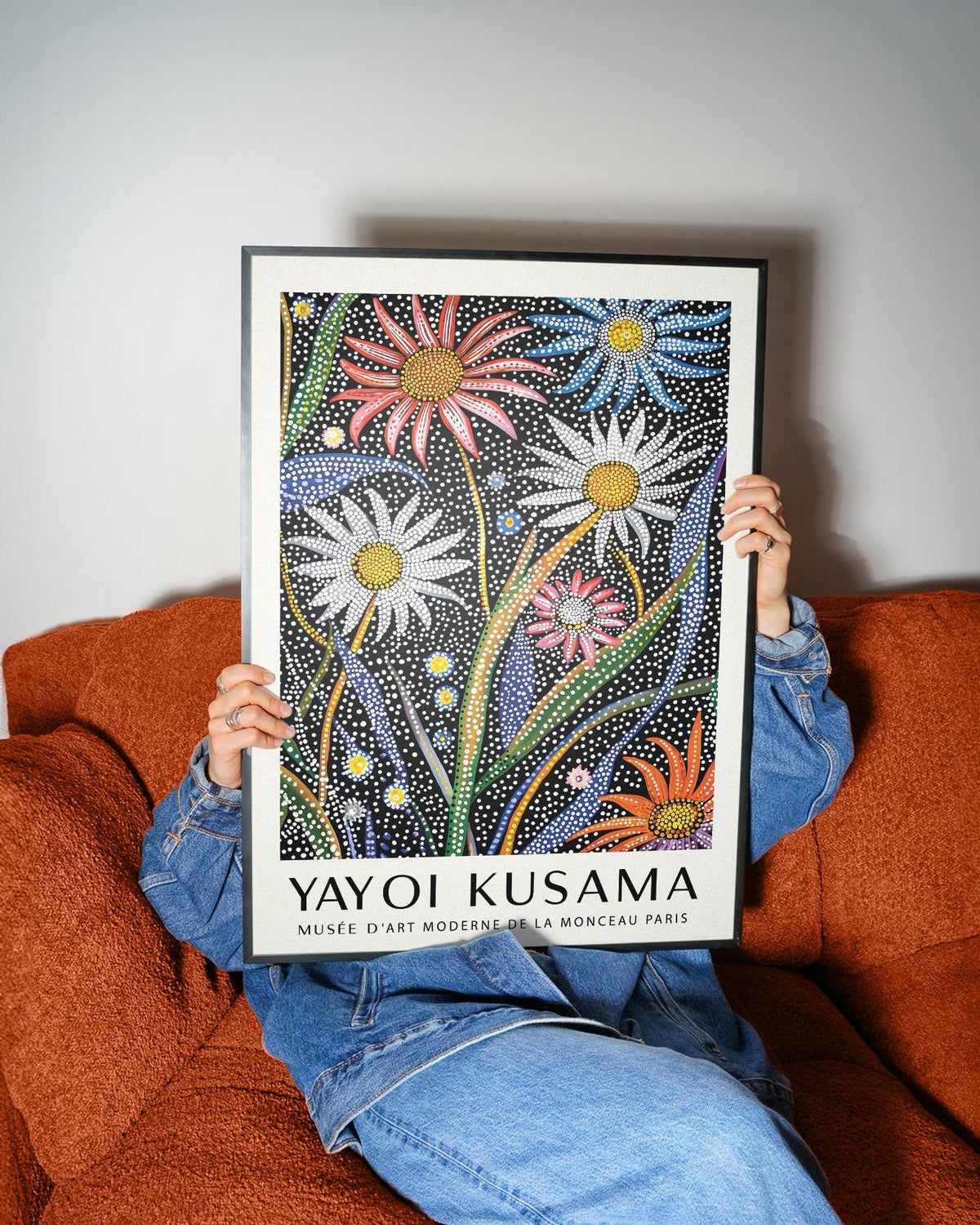 Abstract botanical wall art with dotted flowers in red white and blue held against an orange sofa