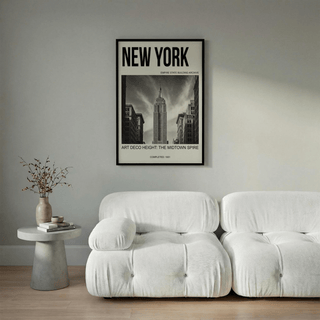 Empire State Building wall art in black and white above a white sofa with a side table and vase