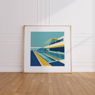 Framed print leaning on floor of modern poolside artwork in blue yellow and cream tones