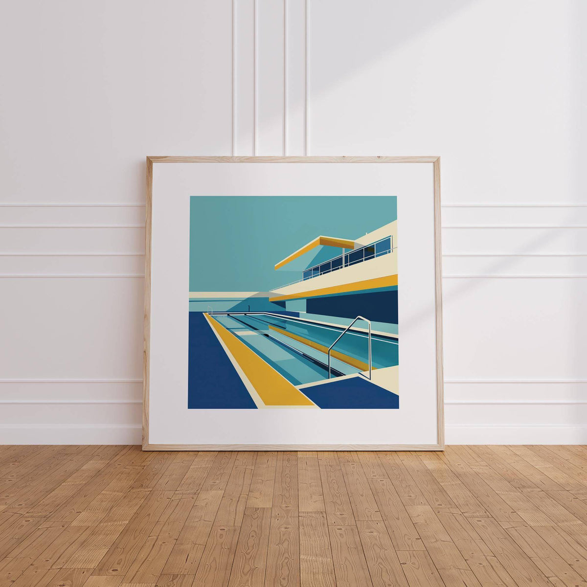 Framed print leaning on floor of modern poolside artwork in blue yellow and cream tones