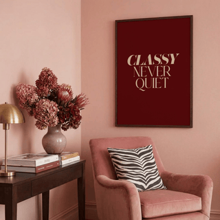 Classy wall art with beige text on dark red above chair with zebra cushion in pink room