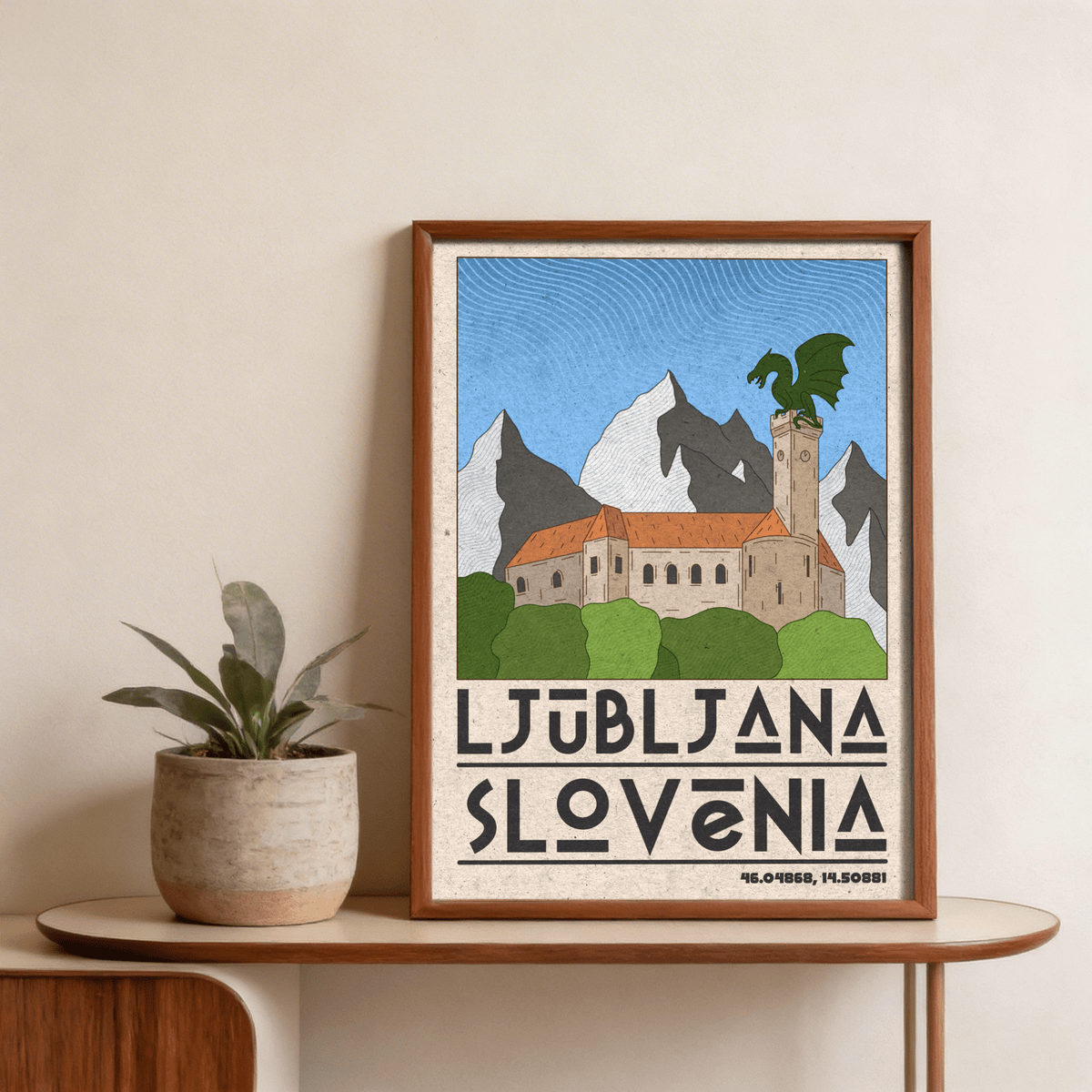 Framed Ljubljana Slovenia art print with a green dragon on a castle tower leaning on a wooden table next to a potted plant