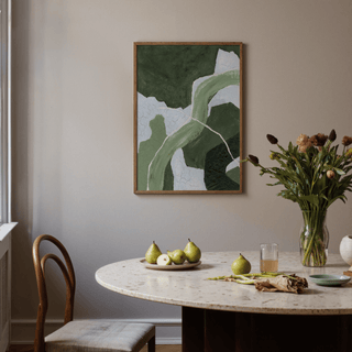 Abstract green art print with flowing shapes framed above a dining table with fruit and flowers