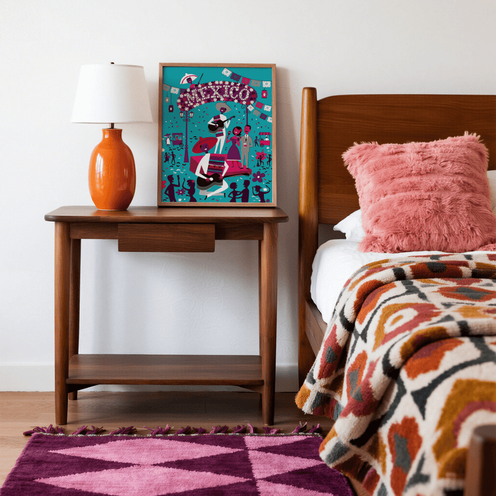Mexican Fiesta wall art leaning on a bedside table with an orange lamp in a bedroom