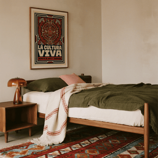 Aztec Culture Art Print framed on a beige wall above a bed with green bedding and a wooden bedside table lamp
