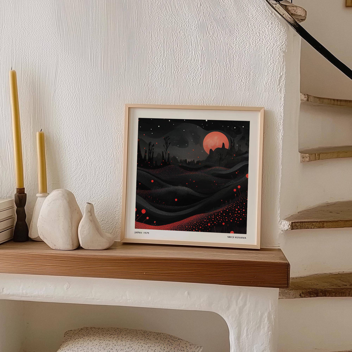 Framed Red Moon Landscape print with black and red abstract design on a wooden shelf with candles