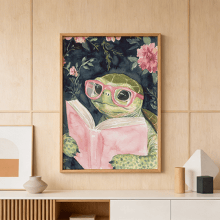 Turtle Reading Art Print of a turtle in pink glasses reading a book above a cabinet with vases in a room