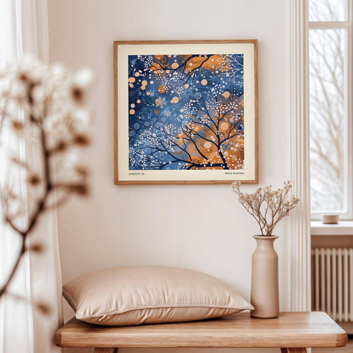 Winter Scene wall art of abstract tree branches with blue and orange hues hanging above a pale pink cushion