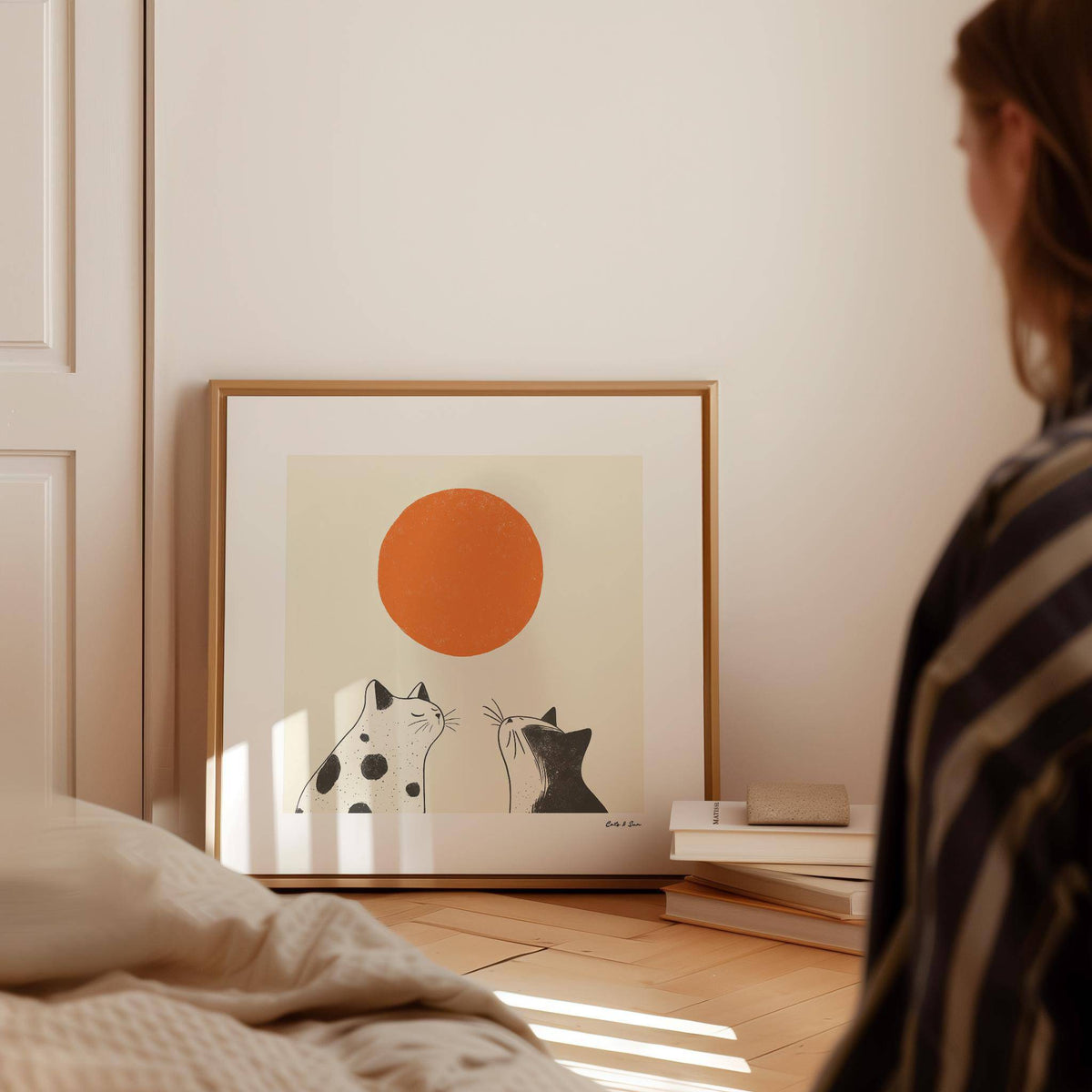 Orange Cat Art print leaning on wooden floor near a wall with books stacked beside it