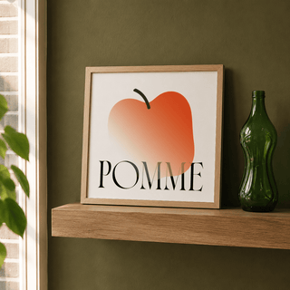 Minimalist Apple Art Print leaning on a wooden shelf with a green bottle beside it