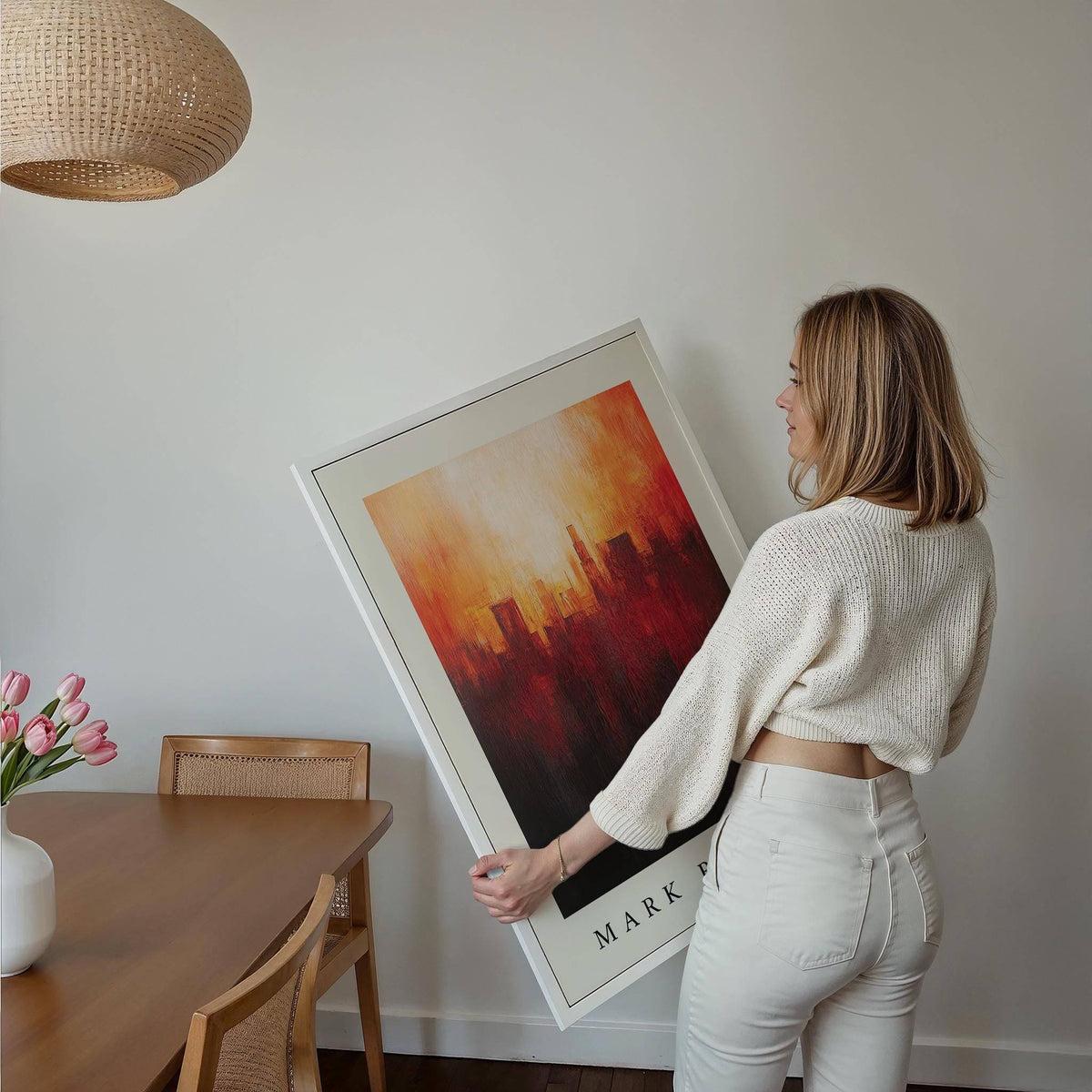 Framed California wall art of an abstract city skyline with fiery red and orange tones held by a woman