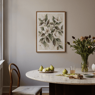 Magnolia wall decor in a wooden frame above a dining table with pears and a vase of flowers