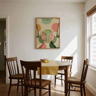 Cozy Matcha Art print of hands holding a green matcha cup above a dining table with wooden chairs