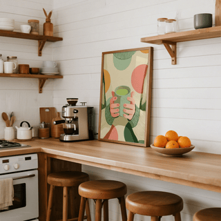 Cozy Matcha Art print leaning on a kitchen counter with wooden stools and a bowl of oranges