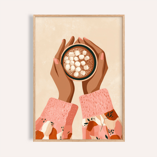 Framed close-up of hot cocoa wall art showing hands holding a cup with pink patterned sleeves