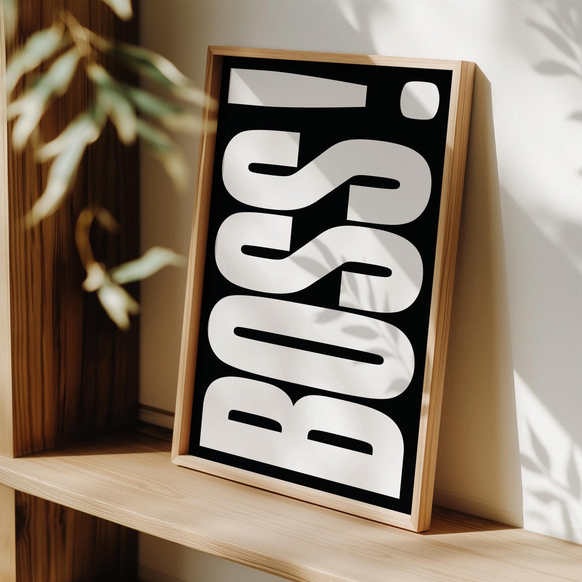 Print leaning on a shelf with BOSS typography in white on black and natural wood frame
