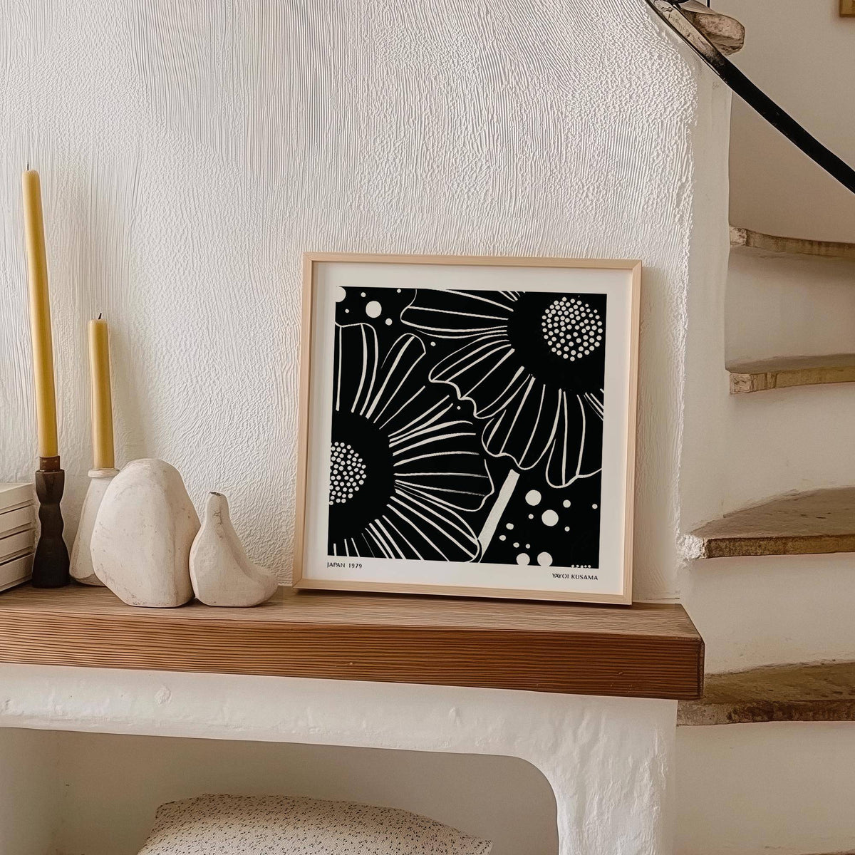 Black White Floral Art print leaning on a wooden shelf with candles and ceramics nearby in a neutral room
