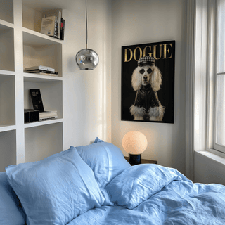 Dog Fashion Print wall art with a poodle in a leather jacket and cap above a bedside lamp