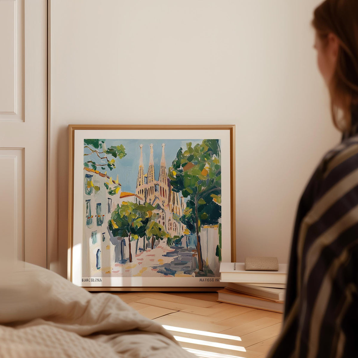 Barcelona Boulevard Poster leaning on a floor with trees and the Sagrada Familia in soft pastel tones next to stacked books