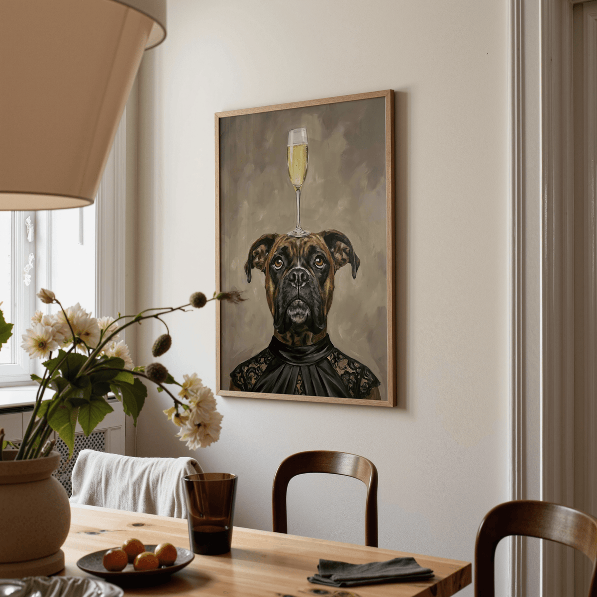 Boxer dog print hanging above a wooden dining table with a lamp and flowers nearby
