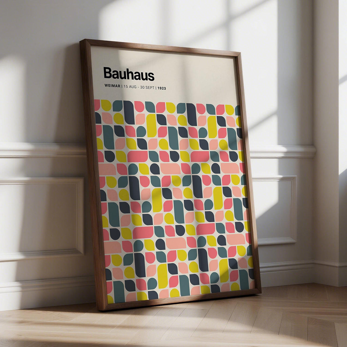 Framed Colorful Wall Poster leaning on a floor with colourful bauhaus geometric shapes in pink yellow and grey