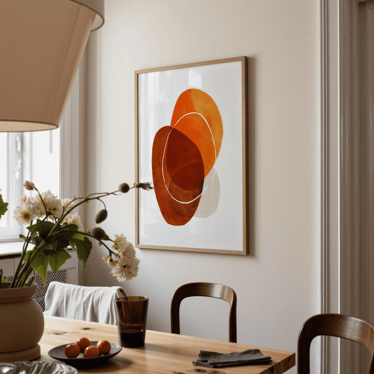Print on a wall of overlapping abstract shapes in warm oranges and browns in a dining room