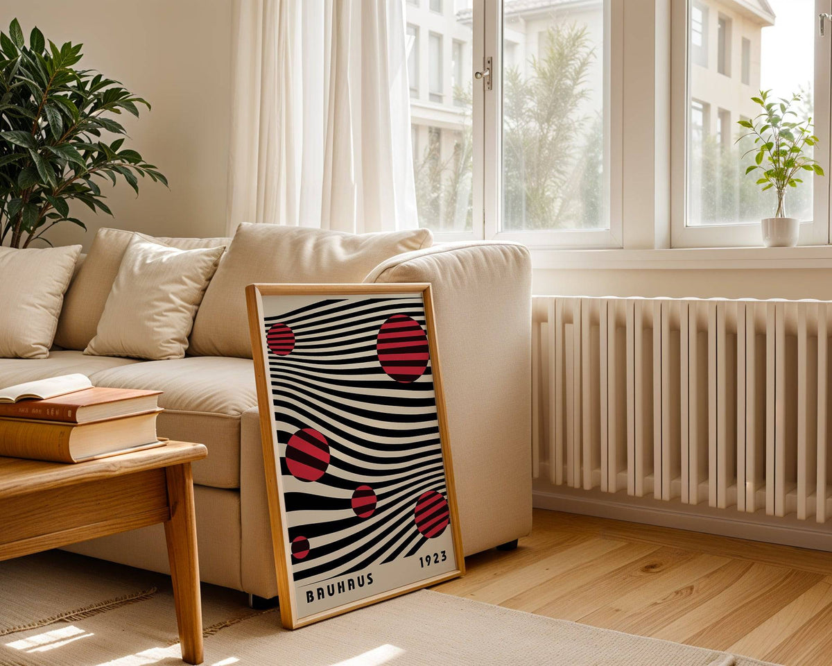 Large Bauhaus wall art with red striped circles on wavy black lines leaning against a sofa