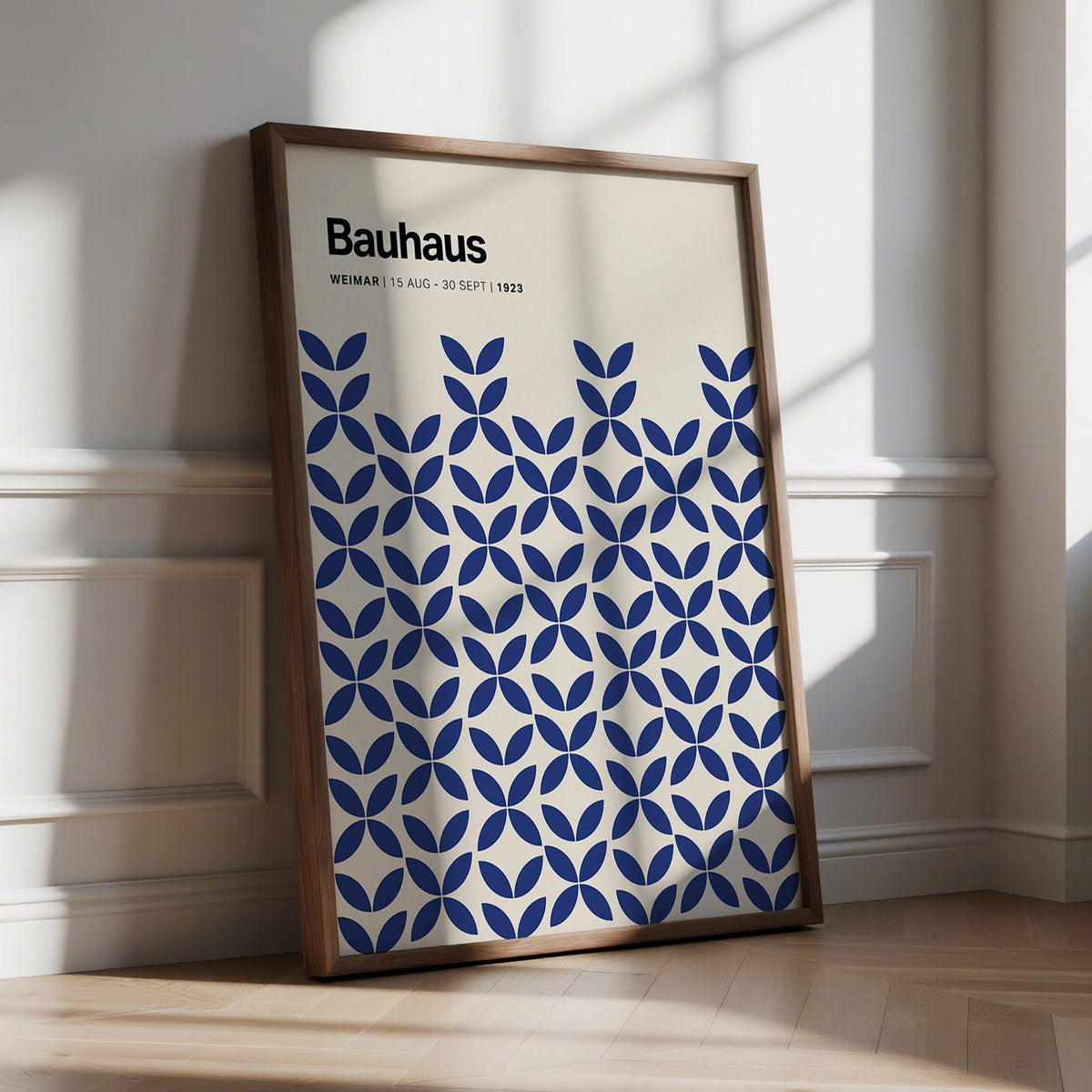 Framed print leaning on floor with indigo blue geometric Bauhaus pattern and typography