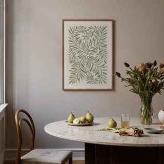 Green leaf art on a wall above a round dining table with pears and a vase of flowers