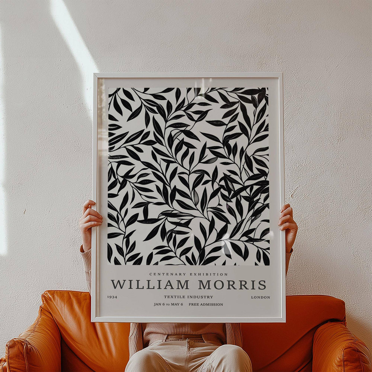 Framed close-up of black and white vintage wall art with botanical-illustration style held on an orange leather chair